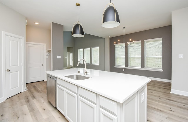 kitchen with stainless steel dishwasher, sink, a center island with sink, white cabinets, and hanging light fixtures