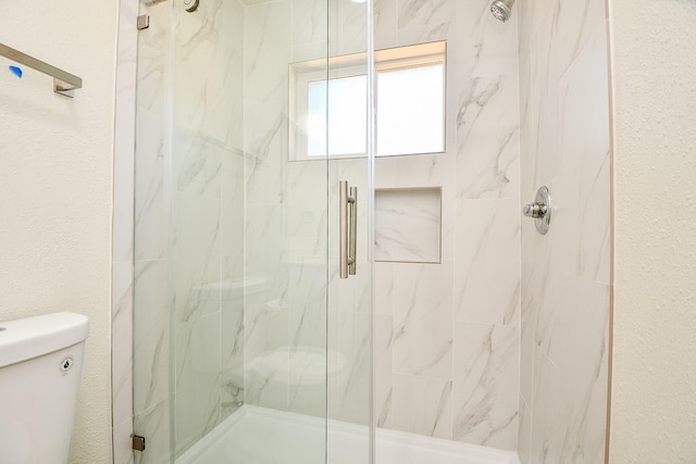 bathroom featuring toilet and a shower with shower door