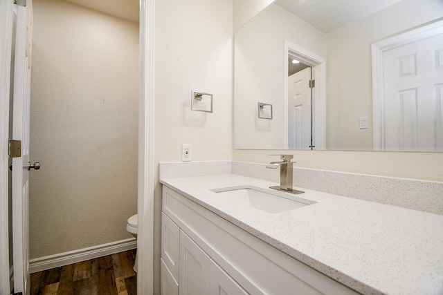 bathroom featuring toilet, hardwood / wood-style flooring, and vanity