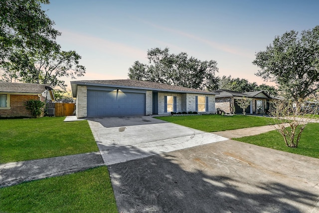 ranch-style home featuring a lawn and a garage