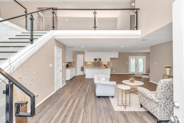 living room featuring light wood-type flooring and a towering ceiling