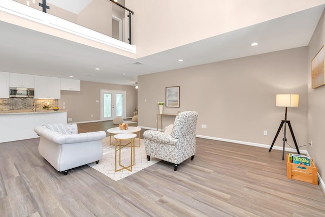 living room featuring a towering ceiling and light hardwood / wood-style flooring