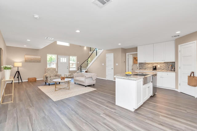 kitchen featuring an island with sink, white cabinetry, sink, and tasteful backsplash