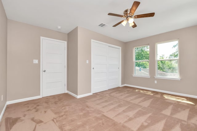 unfurnished bedroom featuring ceiling fan, a closet, and light colored carpet