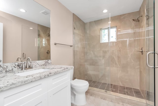 bathroom featuring vanity, a shower with door, and toilet