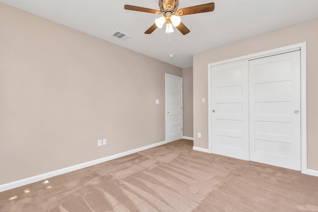 unfurnished bedroom featuring light carpet, a closet, and ceiling fan