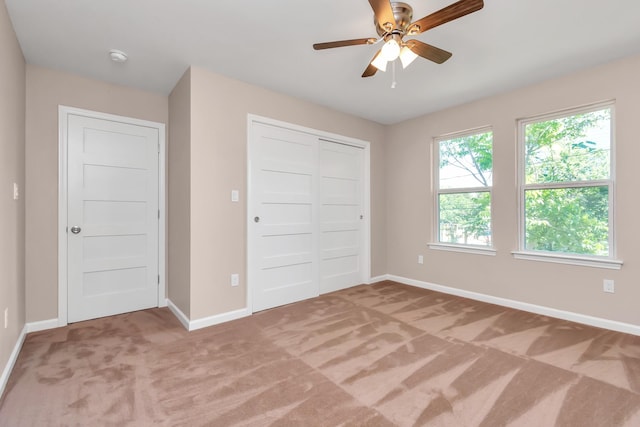 unfurnished bedroom with ceiling fan, carpet flooring, and a closet