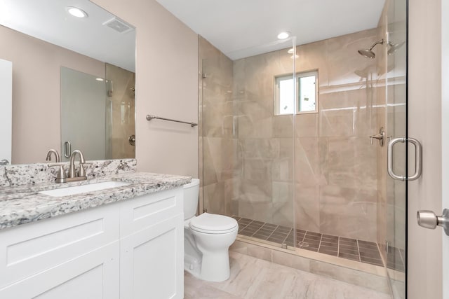 bathroom with vanity, toilet, and a shower with door