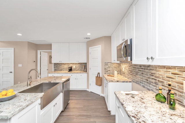 kitchen with sink, white cabinets, stainless steel appliances, and light stone counters