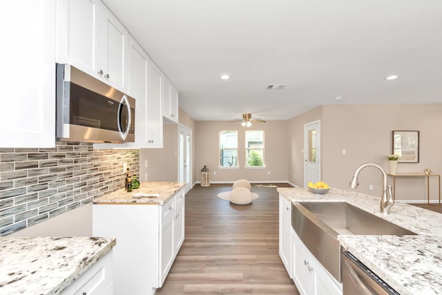 kitchen with appliances with stainless steel finishes, white cabinetry, tasteful backsplash, and sink