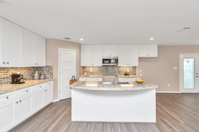 kitchen featuring sink, white cabinetry, an island with sink, and light hardwood / wood-style flooring