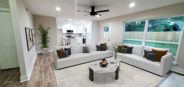 living room with ceiling fan, sink, and light hardwood / wood-style flooring