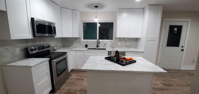 kitchen featuring white cabinets, appliances with stainless steel finishes, backsplash, and light stone counters