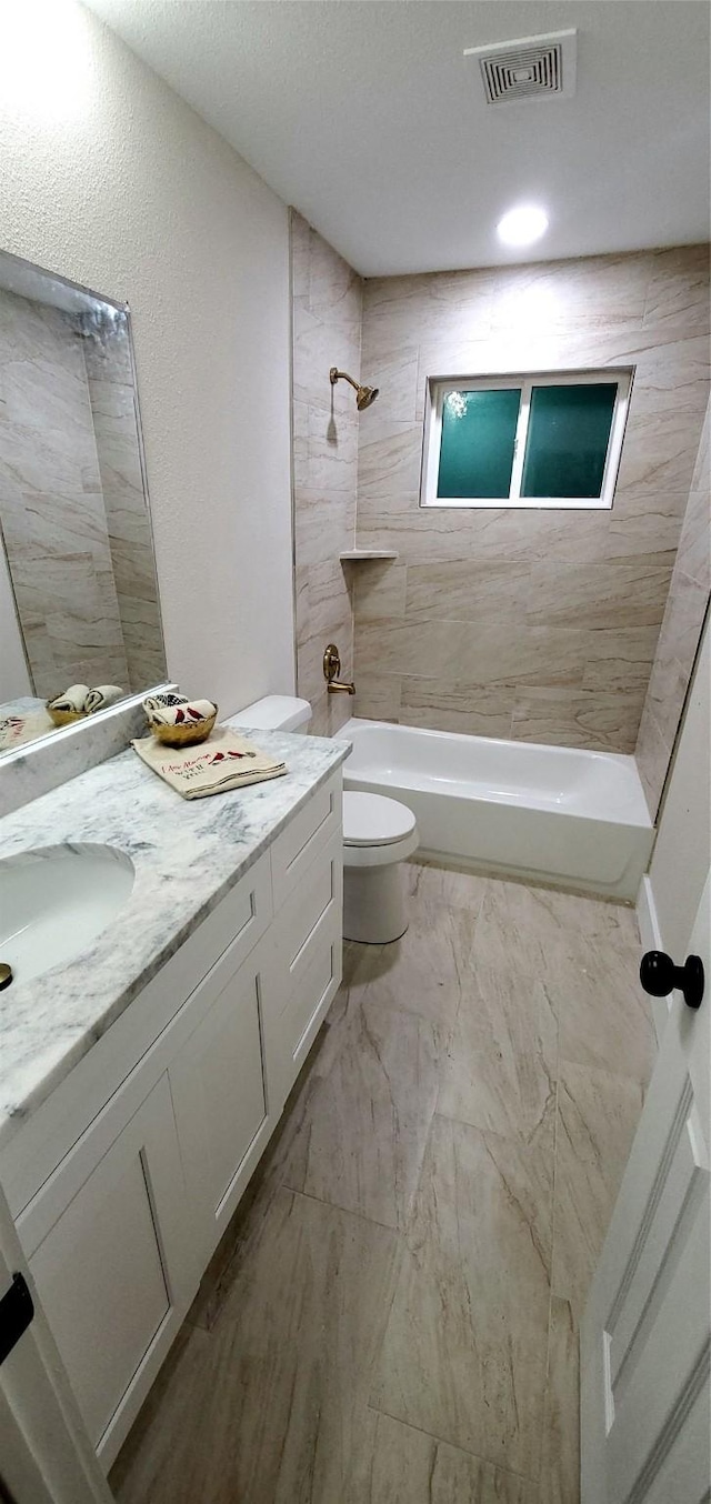 full bathroom with tiled shower / bath combo, toilet, and vanity