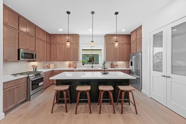 kitchen with decorative backsplash, light wood-type flooring, premium appliances, a kitchen island, and a breakfast bar area