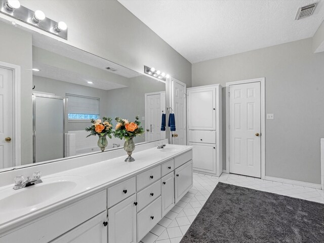 bathroom featuring an enclosed shower, vanity, tile patterned flooring, and a textured ceiling