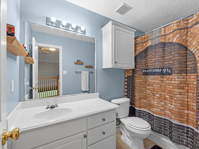 bathroom featuring a textured ceiling, toilet, and vanity