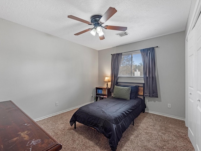 carpeted bedroom featuring ceiling fan, a closet, and a textured ceiling