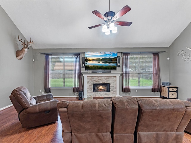 living room with ceiling fan, hardwood / wood-style flooring, lofted ceiling, and a stone fireplace