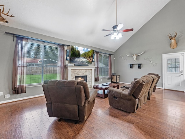 living room with hardwood / wood-style flooring, high vaulted ceiling, ceiling fan, and a fireplace