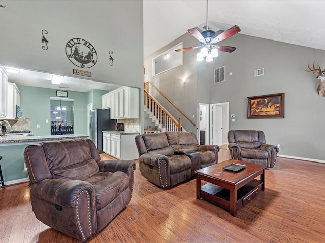 living room with ceiling fan, wood-type flooring, and high vaulted ceiling