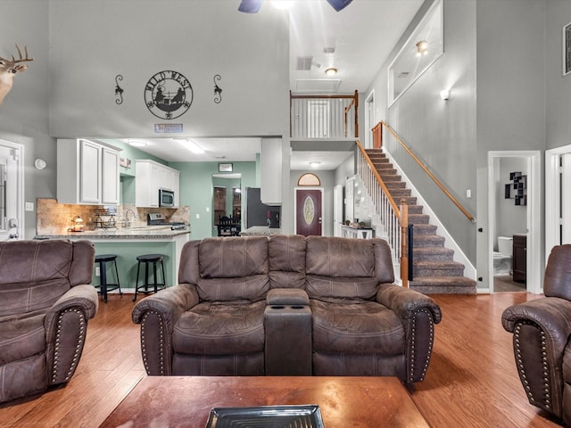 living room featuring light wood-type flooring, a high ceiling, and sink