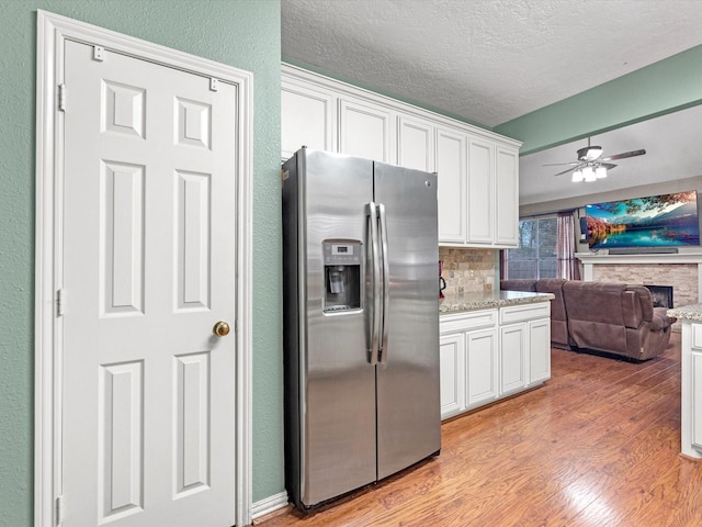 kitchen with light hardwood / wood-style floors, white cabinets, backsplash, and stainless steel fridge