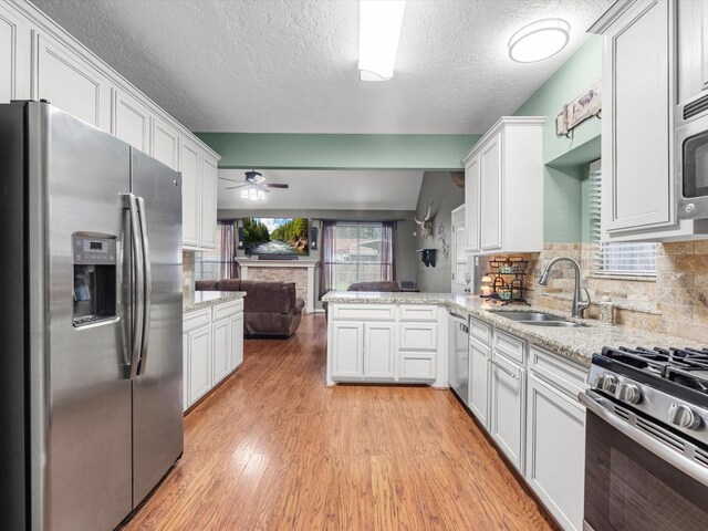 kitchen with white cabinetry, stainless steel appliances, decorative backsplash, sink, and ceiling fan