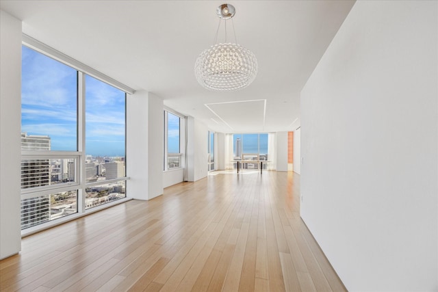 interior space with expansive windows, a chandelier, and light hardwood / wood-style floors