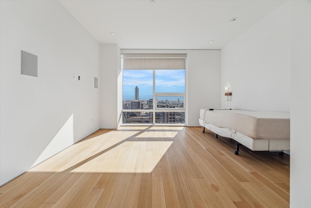 bedroom with light hardwood / wood-style floors and a wall of windows