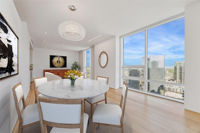 dining room with light wood-type flooring, an inviting chandelier, and expansive windows