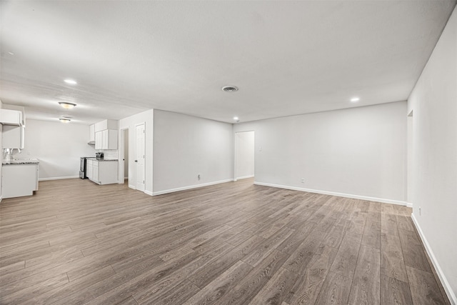 unfurnished living room featuring light hardwood / wood-style floors and sink