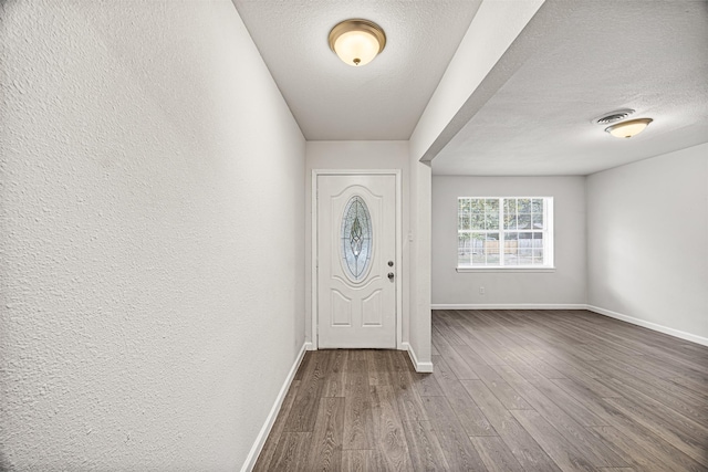 entryway with wood-type flooring and a textured ceiling