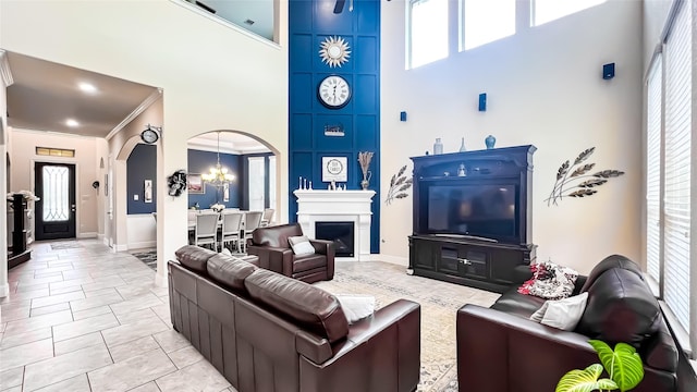 living room with a notable chandelier, light tile patterned floors, ornamental molding, and a high ceiling