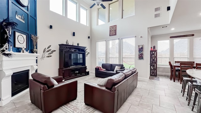 living room featuring ceiling fan, light tile patterned flooring, and a high ceiling