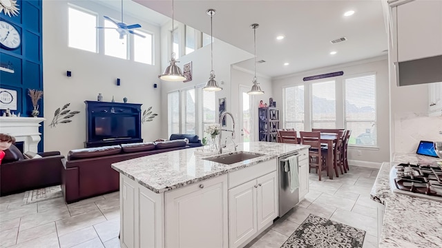 kitchen with stainless steel appliances, a kitchen island with sink, sink, decorative light fixtures, and white cabinets