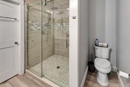 bathroom featuring hardwood / wood-style flooring, toilet, and an enclosed shower