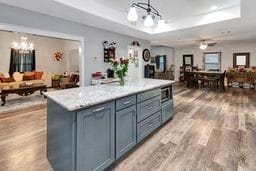 kitchen with ceiling fan, wood-type flooring, decorative light fixtures, a center island, and stainless steel microwave