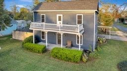 rear view of property with a lawn, a patio area, and a balcony