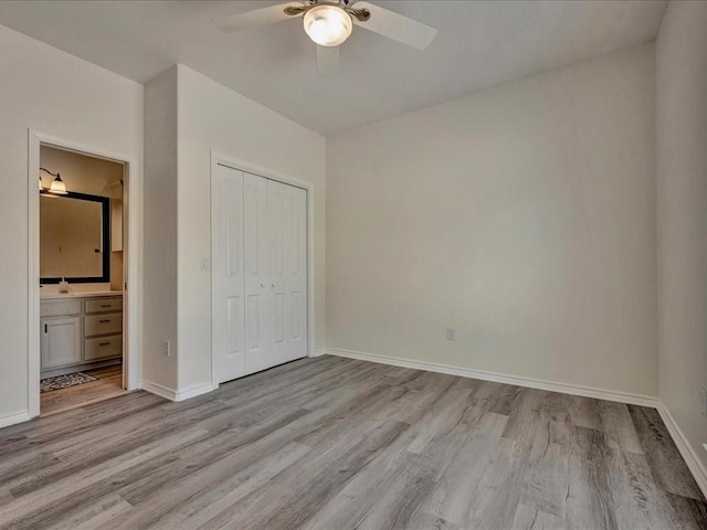 unfurnished bedroom featuring ensuite bath, ceiling fan, a closet, and light wood-type flooring