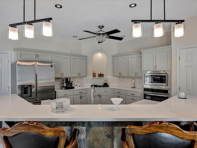 kitchen featuring a breakfast bar area, tasteful backsplash, pendant lighting, and appliances with stainless steel finishes