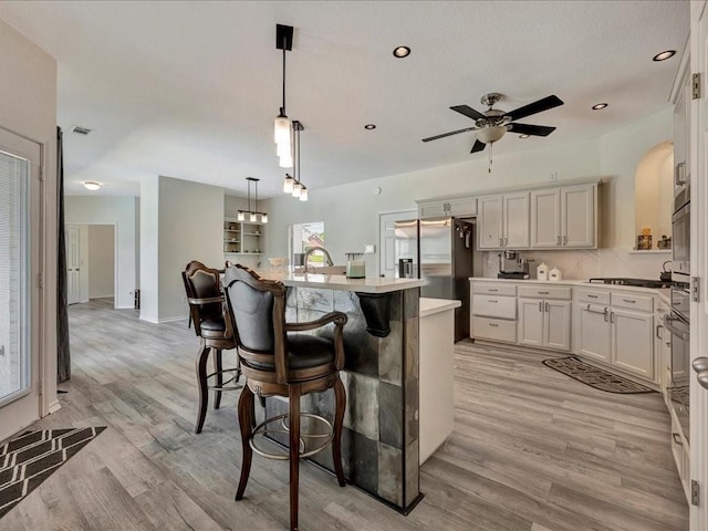 kitchen featuring stainless steel fridge with ice dispenser, white cabinetry, a kitchen island, and light hardwood / wood-style floors