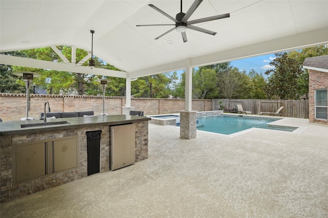 view of pool featuring sink, an in ground hot tub, ceiling fan, exterior kitchen, and a patio