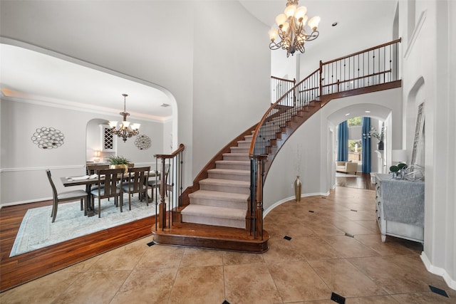 entrance foyer with ornamental molding, tile patterned floors, a chandelier, and a high ceiling