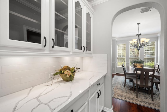 bar featuring white cabinetry, decorative light fixtures, dark wood-type flooring, and light stone counters