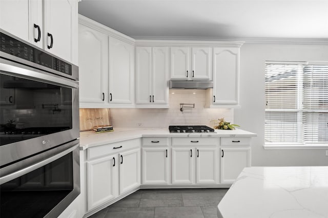 kitchen with white cabinetry, appliances with stainless steel finishes, and light stone counters