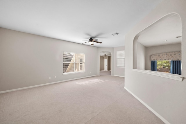 carpeted spare room featuring a wealth of natural light and ceiling fan