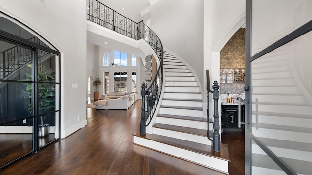 foyer entrance featuring dark wood-type flooring and a towering ceiling