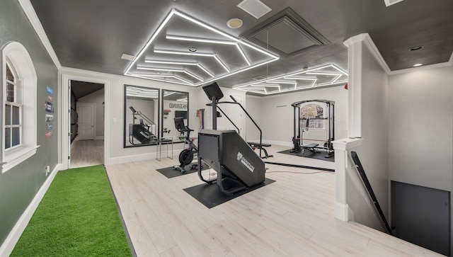 workout area with light wood-type flooring and crown molding