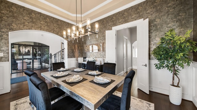 dining space featuring a towering ceiling, dark wood-type flooring, crown molding, and a chandelier